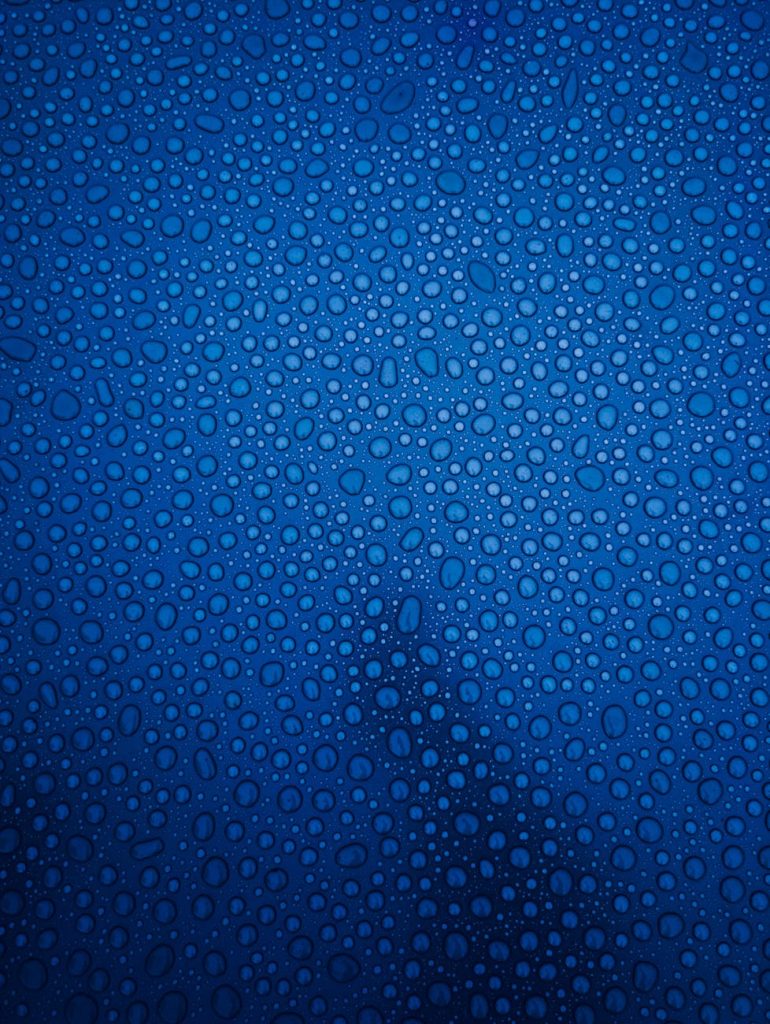 Macro shot of water droplets on a blue glass surface in Victoria, BC.
