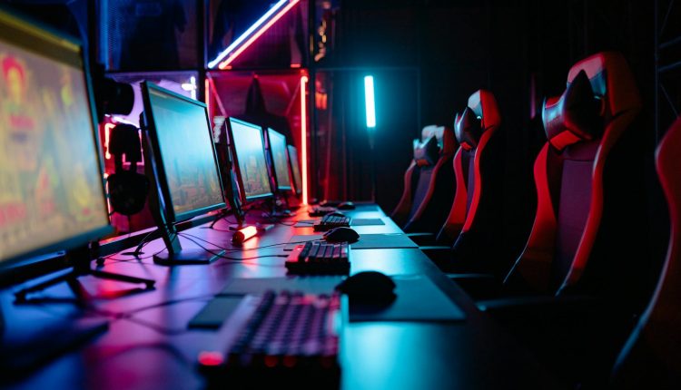 An immersive gaming room with neon lights, computers, and gaming chairs ready for a tournament.