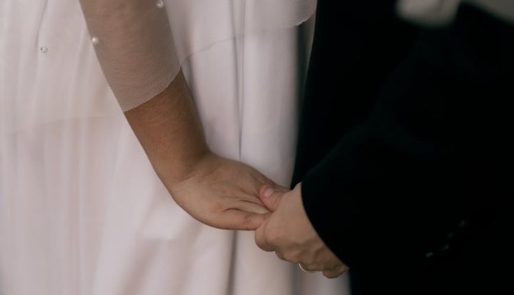 Close-up of a couple holding hands on their wedding day, symbolizing love and commitment.